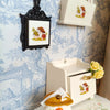 A handcrafted miniature mushroom tableware set displayed on a white cloth next to a decorative wall mount.