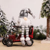 A festive Christmas decoration featuring an illuminated LED gnome doll with a white beard and winter outfit sitting on a vint