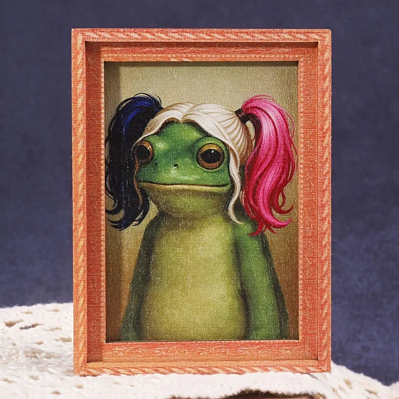 A cute green frog character is displayed inside a wooden photo frame.