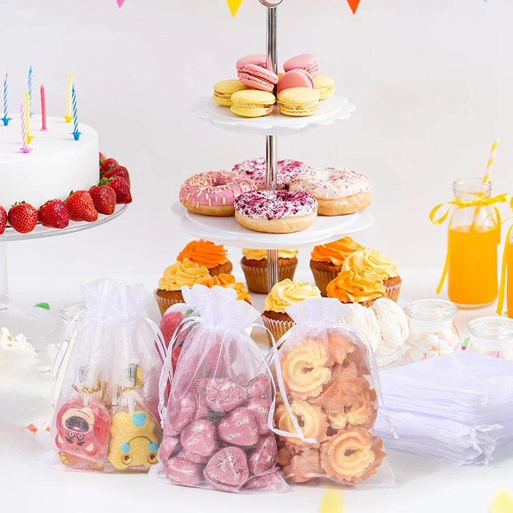 Elegant white and gold drawstring organza bags filled with various treats for gifts and parties