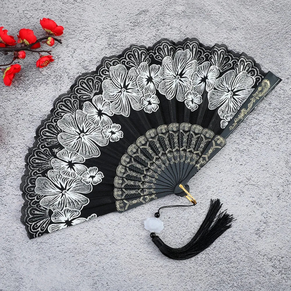 A black and white antique folding fan decorated with detailed bamboo flower patterns.