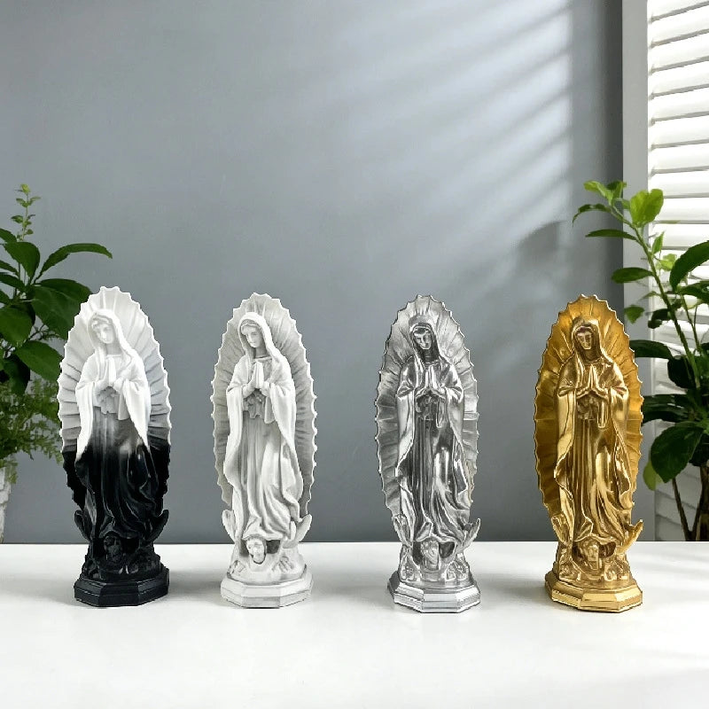 A row of four resin statues depicting Our Lady of Guadalupe in various finishes including black, silver, and gold.