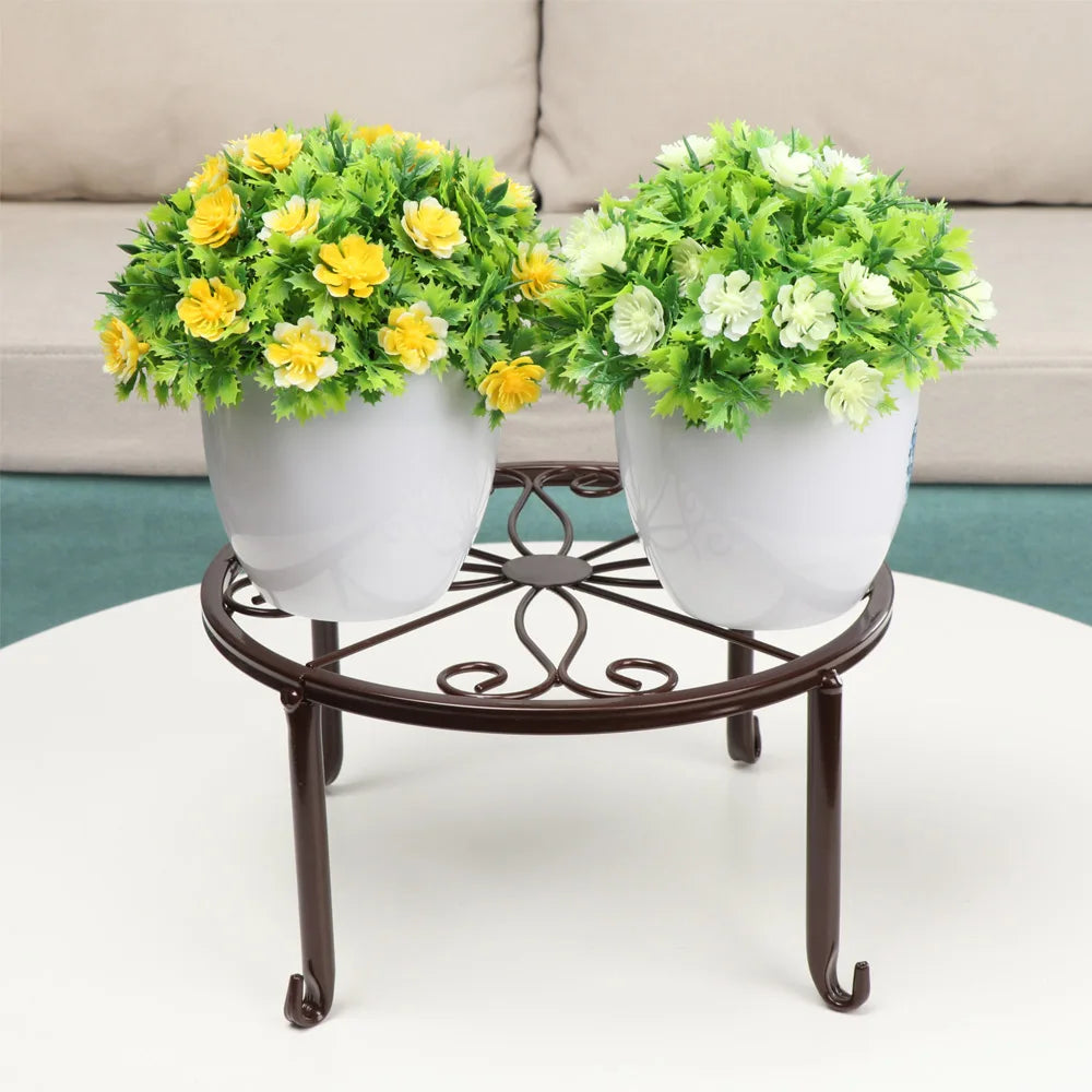 A decorative metal plant stand holding two potted green and yellow flowering plants.