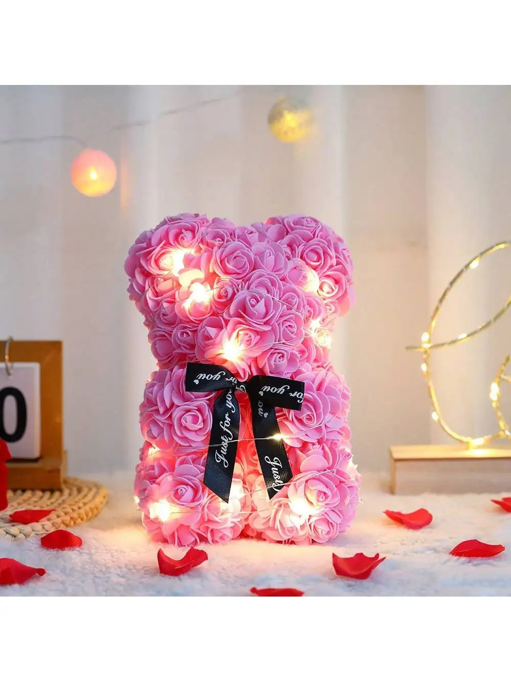Pinker künstlicher Rosen-Teddybär mit leuchtenden Lichtern auf weißem Untergrund.