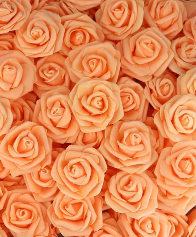 A close-up view of numerous artificial foam roses in various shades of peach and orange.