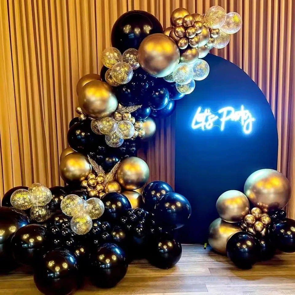 A vertical arrangement of black and gold latex balloons creating a decorative backdrop.