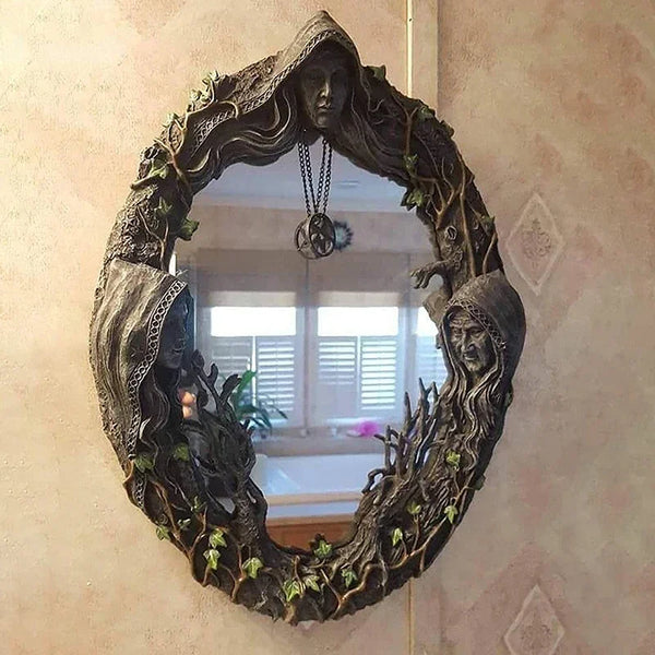 A dark, leafy wreath mirror framed in wood hangs on a wall, featuring an amulet.