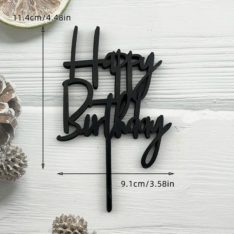 Black acrylic birthday cake topper with the words Happy Birthday on a white wooden background.