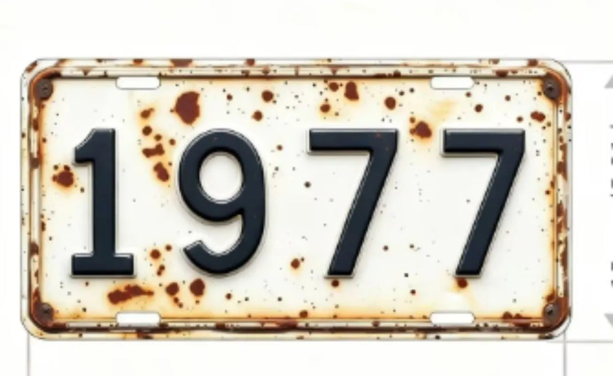A vintage aluminum license plate tag with the year 1977 showing signs of wear and patina.