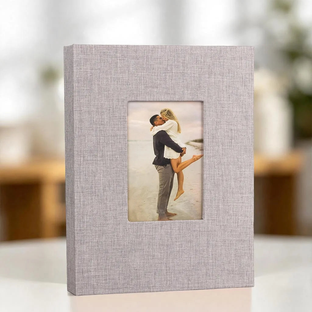 A square linen photo album with a front display window showing a couple embracing.