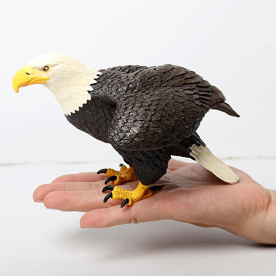 A realistic figurine set featuring an owl, vulture, and bald eagle perched on a human hand.