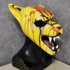 A yellow latex mask shaped like a tiger's head with blood splatters and fangs, displayed on a black bust.