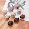 A collection of natural crystal heart carvings in pink, white, and dark brown tones displayed on a light background.
