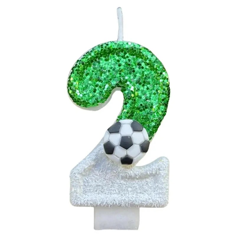 A custom number birthday candle shaped like the number 2, covered in green glitter and topped with a soccer ball decoration.