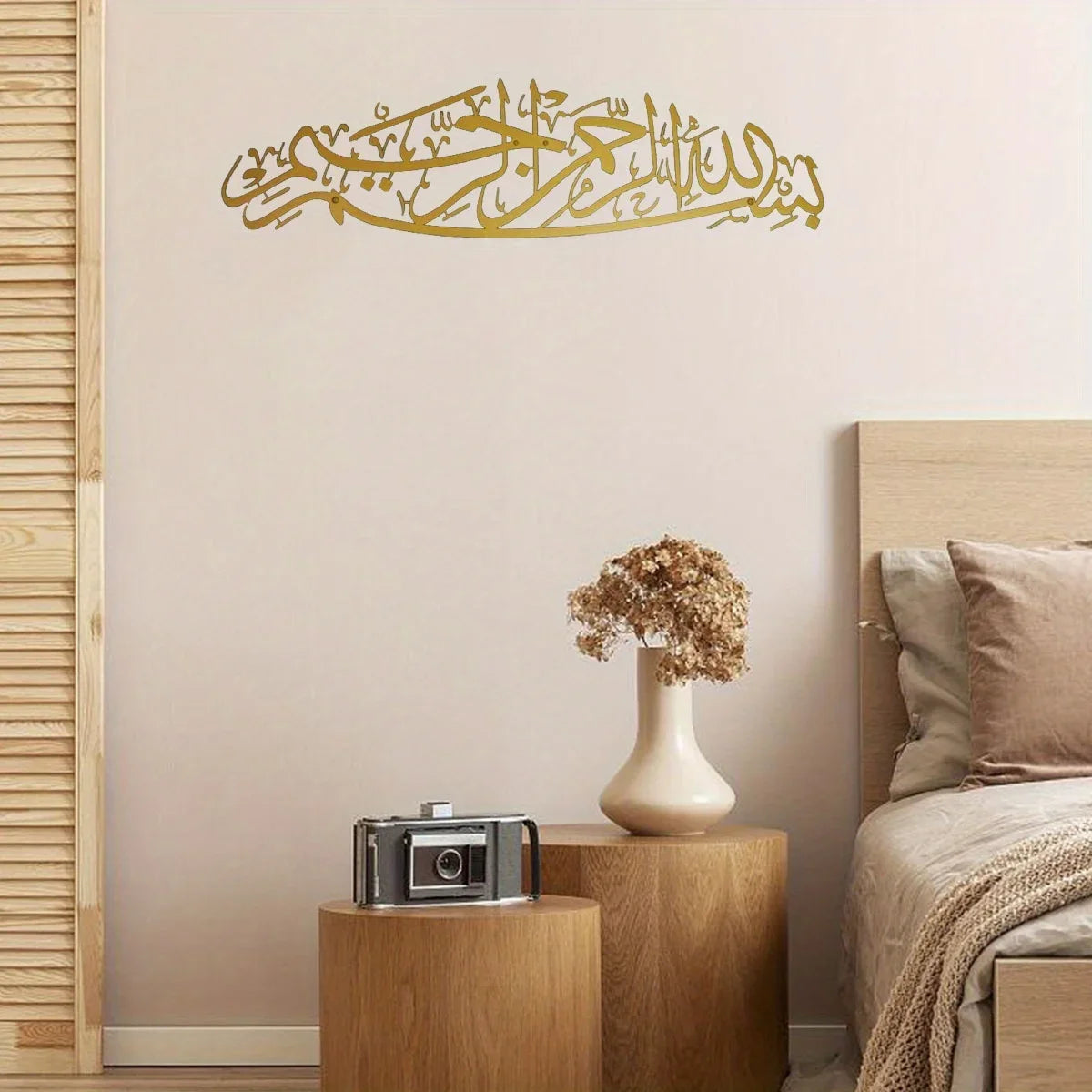 Gold calligraphy wall art featuring the Bismillah in Arabic script mounted on a light beige wall.