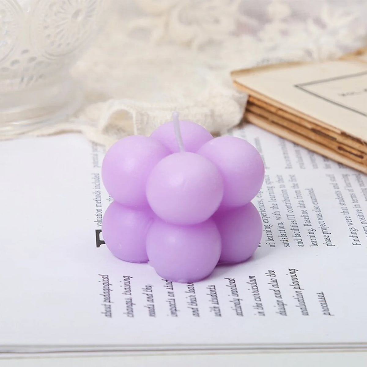 A set of two white and pink cube soy wax candles resting on a white notebook.