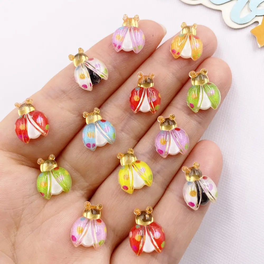 A hand displays several colorful resin beetle rhinestone appliques for DIY crafts.
