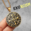 A gold-toned stainless steel punk cross necklace with Latin inscription on a dark background.