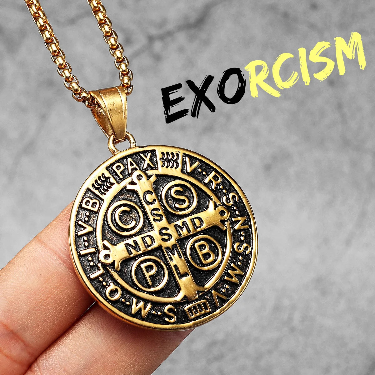 A gold-toned stainless steel punk cross necklace with Latin inscription on a dark background.