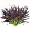A close-up of a dark purple and green artificial tall grass and tropical flower arrangement.