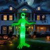 A glowing green inflatable alien decoration standing in a front yard at night with pumpkins and Halloween decor.