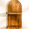 A vertical wooden wall shelf with a curved, ribbed design and a horizontal shelf.