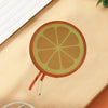 A round fruit design, resembling an orange slice, is shown on a light wooden surface.
