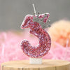 Pink glitter birthday number three candle with a silver crown topper