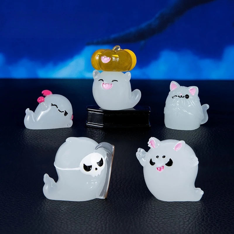 A set of seven white luminous ghost resin ornaments, including a pumpkin-shaped piece, displayed against a dark background.