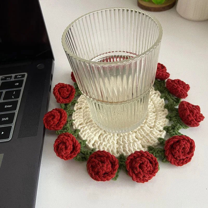 Hand-crocheted red rose flower coasters arranged around a clear glass