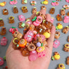 A hand holds numerous small, colorful capybara-themed figures and accessories.