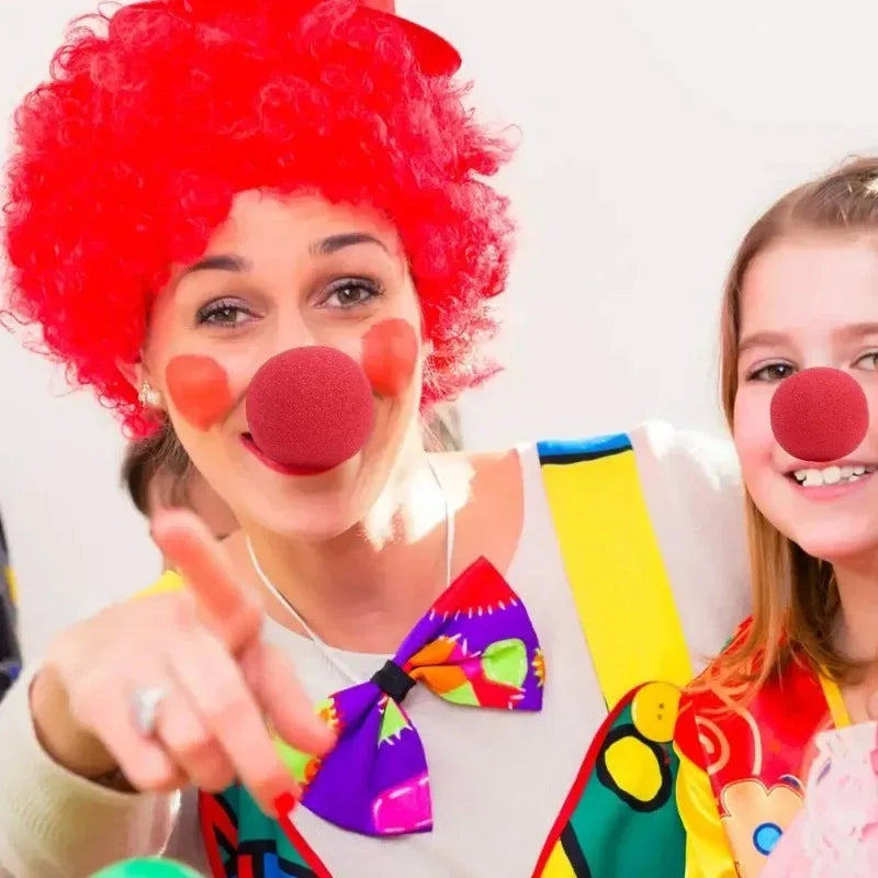 A woman wearing a bright red curly wig and a foam clown nose is shown smiling.