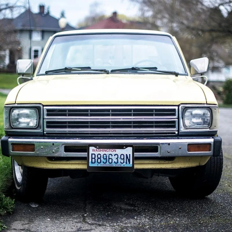 A yellow classic car with a Washington license plate mounted on the front bumper.
