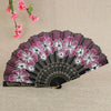 A folding fan with a black background featuring pink and white floral patterns.