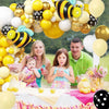 A colorful bee-themed balloon arch set featuring yellow, black, and white balloons decorated with a family.