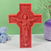 A red silicone mold of a crucifix featuring Jesus with a halo and outstretched arms.