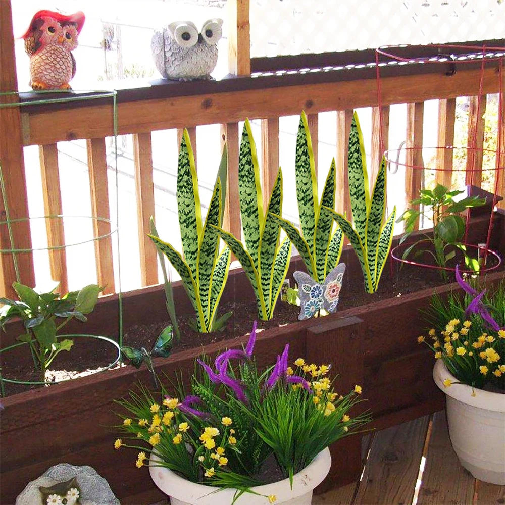 Planta de serpiente artificial en maceta con flores amarillas y moradas, exhibida en una barandilla de madera