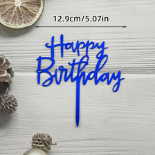 Blue acrylic birthday cake topper with happy birthday lettering and a gold slice of citrus fruit