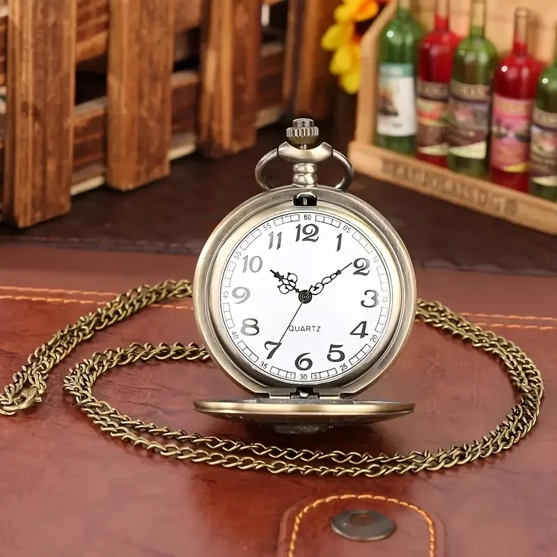 A vintage bronze quartz pocket watch with a chain resting on a brown leather surface.