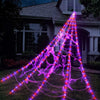Purple Halloween spider web lights illuminating a house exterior at night
