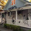 A black spider decoration is displayed on the siding of a house under a pitched roof.