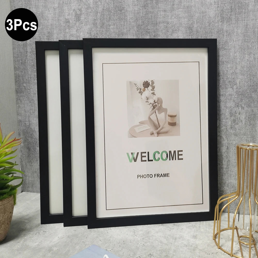 Three black photo frames with white mats displayed against a gray wall.