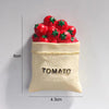 A small beige pouch filled with red tomato fridge magnets and a gold tomato label.