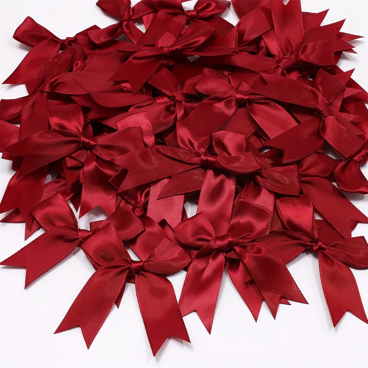 A pile of elegant red satin ribbon bows for gift wrapping and decor.