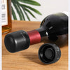 A black silicone wine bottle stopper is shown next to a glass bottle on a wooden surface.