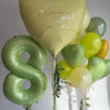 A bouquet of vintage number balloons shaped like the letter B and various green and yellow balloons for birthday decor