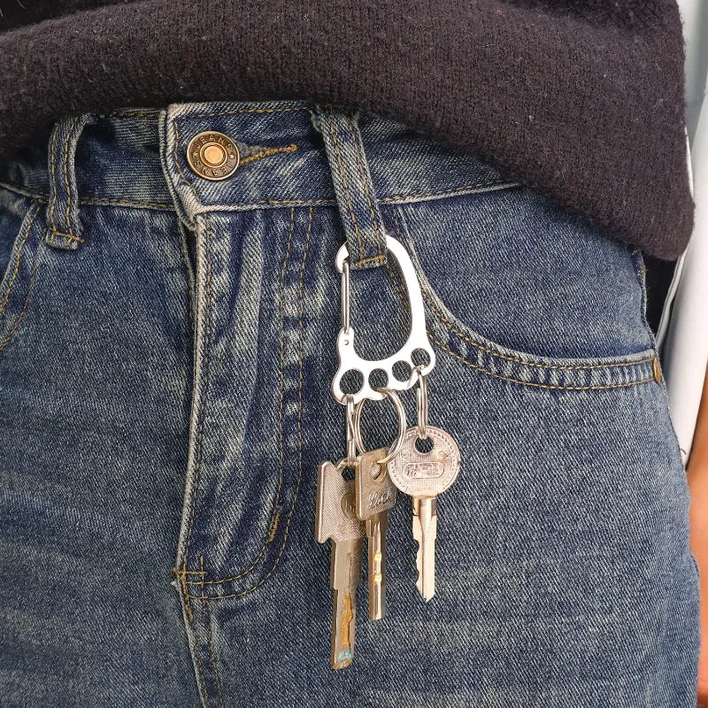 A close-up of a durable stainless steel keychain with multiple loops attached to a pair of blue denim jeans.