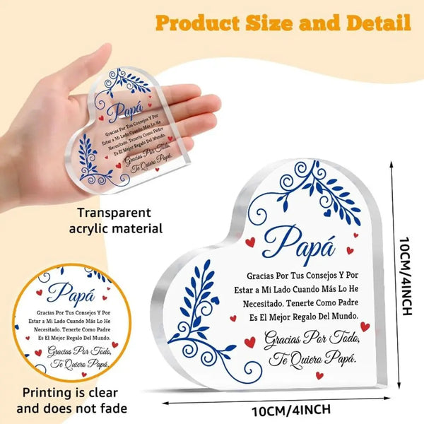 A hand holds a clear acrylic heart plaque with decorative script on it, demonstrating the product size.