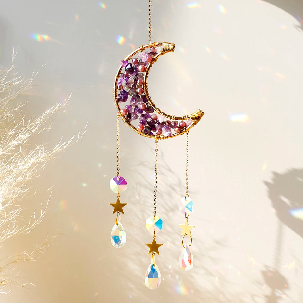A gold crescent moon dreamcatcher adorned with purple crystals and hanging charms.