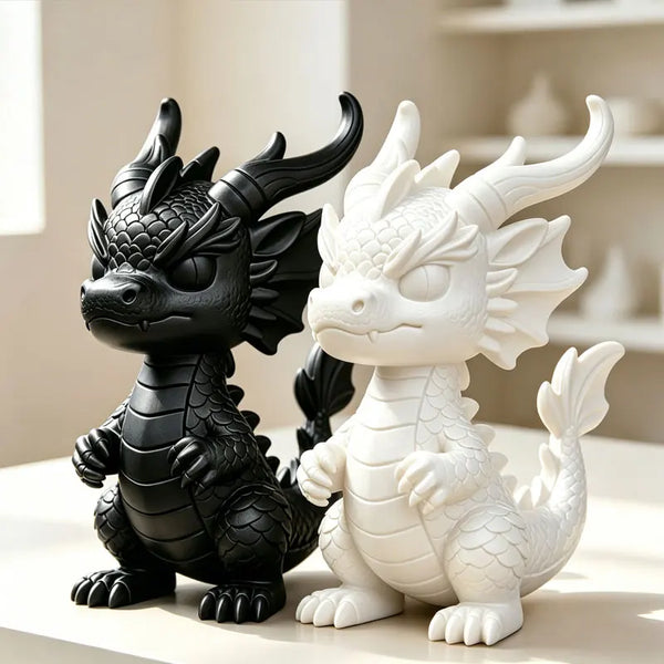 A pair of 3D printed mini dragon statues, one black and one white, displayed on a light surface.